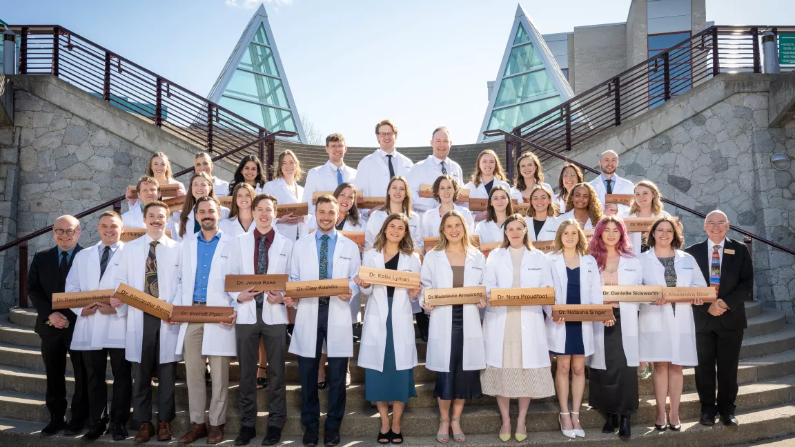 The NMP Class of 2024 in white coats and holding their cedar shingles.