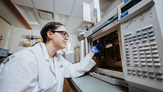 Mya Schouwenburg  in a lab working with a piece of equipment 