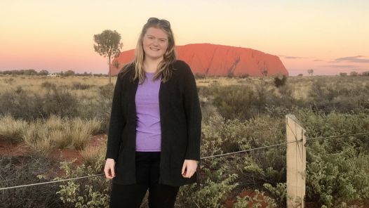 A UNBC student stands in front of Uluru, also known as Ayers Rock, in Australia. 