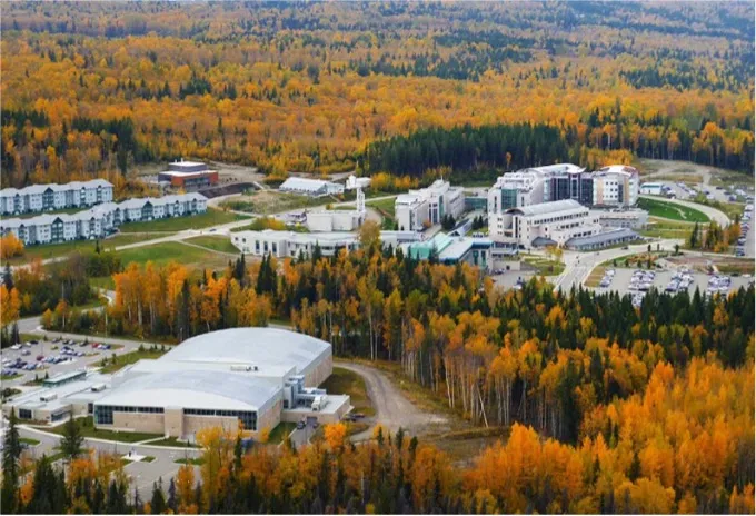 Aerial view of UNBC Prince George campus in autumn, surrounded by a landscape of golden trees.