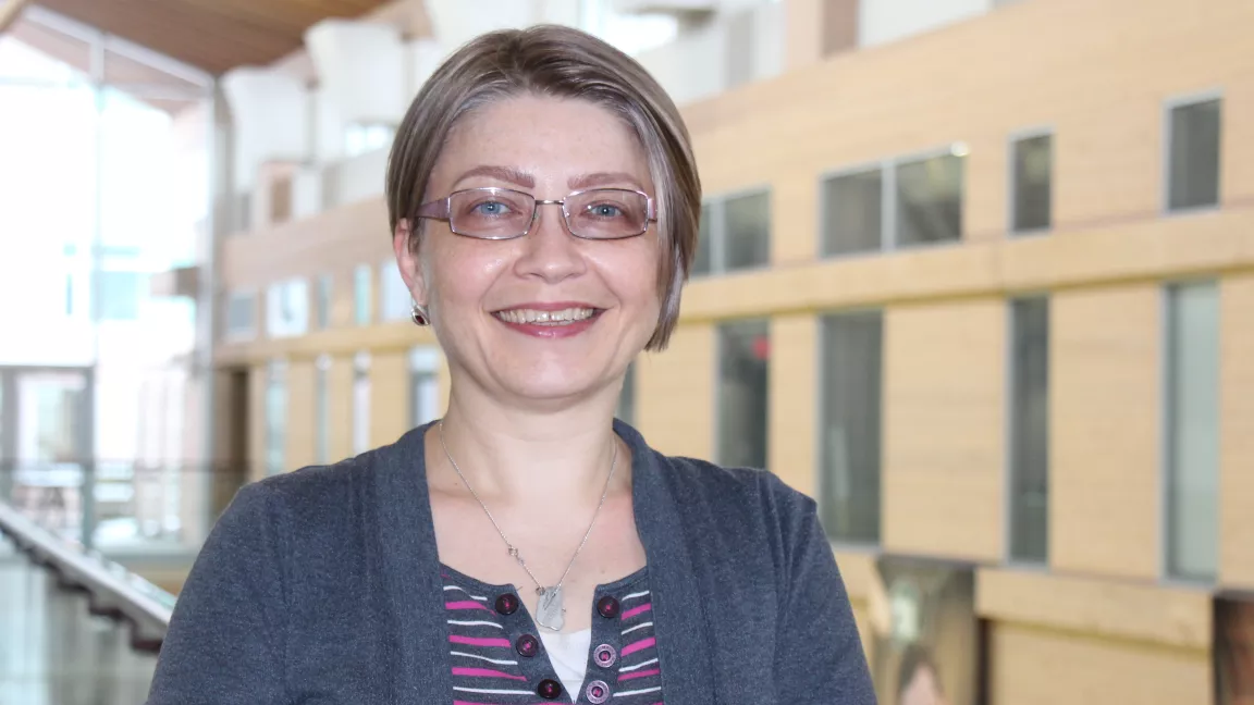 Dr. Alina Constantin stands in front of a atrium backdrop