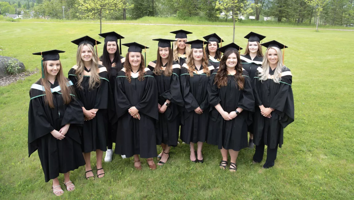 Group photo of all graduates from the South-Central campus in Quesnel. Graduates are wearing cap and gowns, photo is outside.