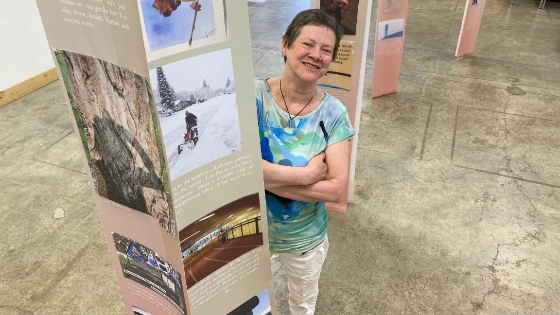 Dr. Theresa Healy looking up towards the camera with a photography exhibit next to her