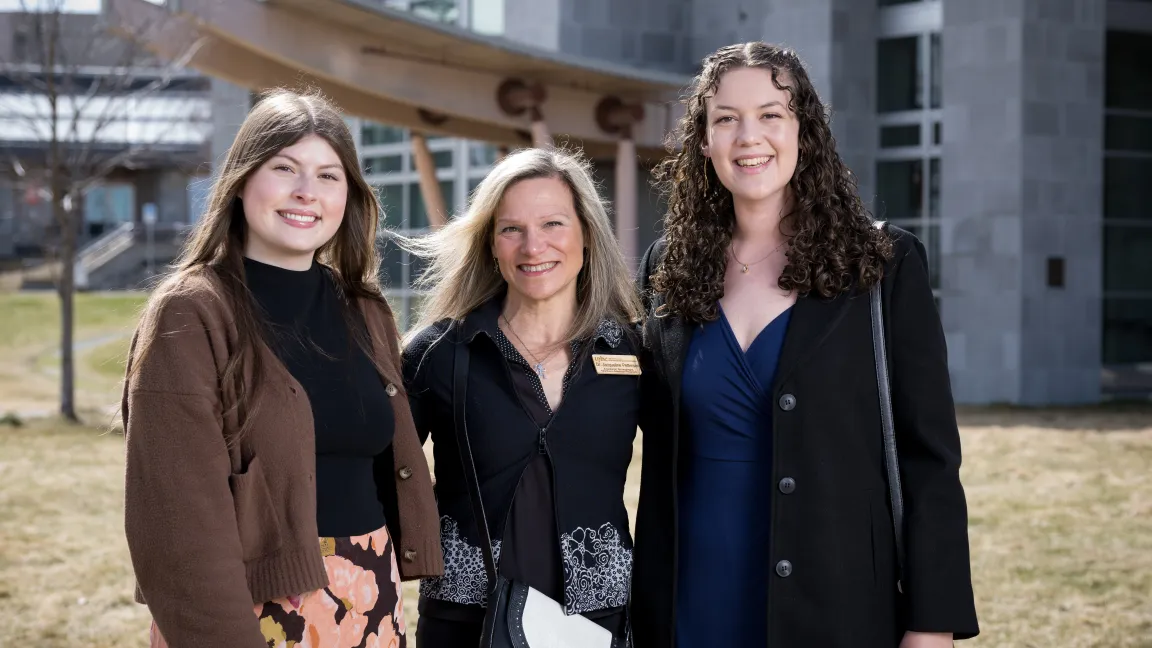 Dr. Jacqui Pettersen stands outdoors on a lawn together with UNBC graduate Jenna Rea and NMP graduate Katherine Bailey.