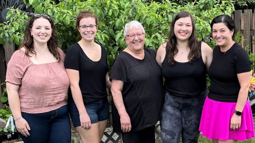 Five members of the Hauck family stand together outdoors with green bushes behind them.