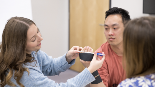 Two occupational therapy students practice a clinical skill in the classroom.