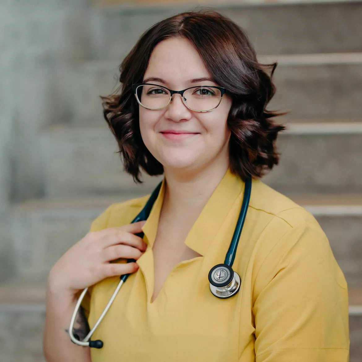 NMP Class of 2024 graduate Dr. Ali Blair dressed in yellow scrubs.