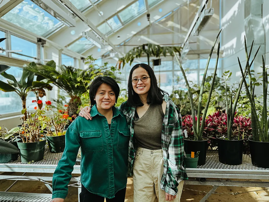 Two women standing together in UNBC greenhouse