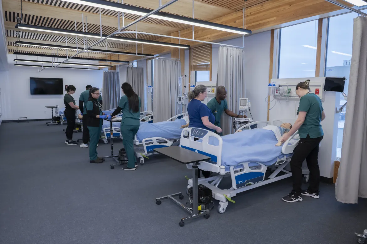 Students administering care to mannequin patients during a lab session. 