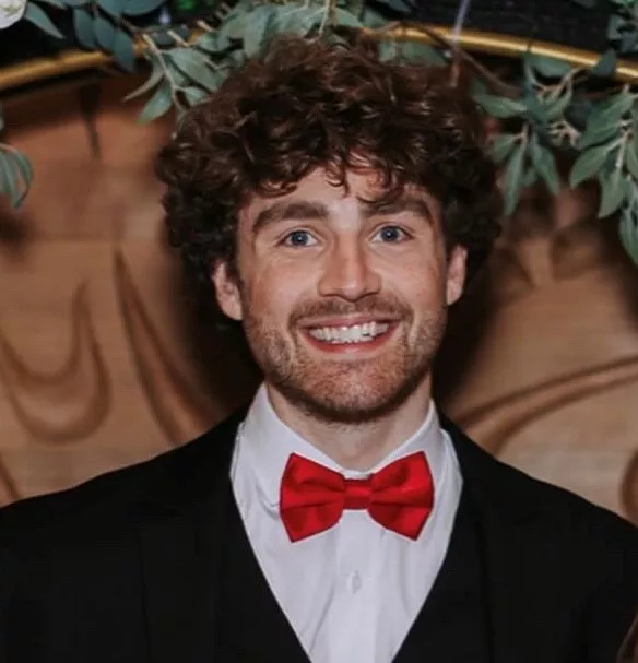 A individual wearing a suit and red bowtie.