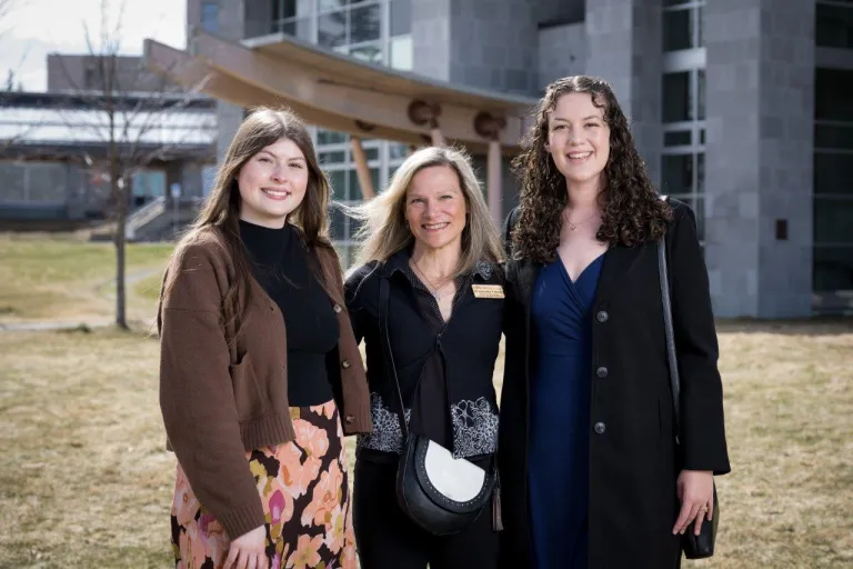 Researcher with two students in front of the NHSC building.