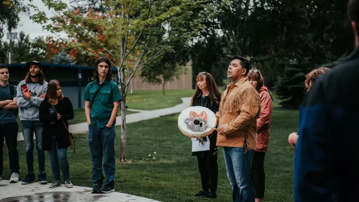Students listening to a man playing a drum