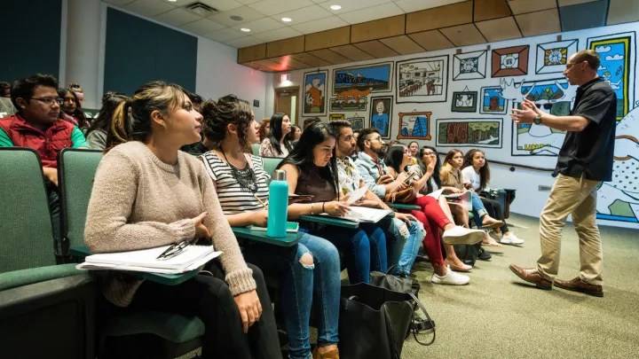 Students in class listening to a teacher presenting