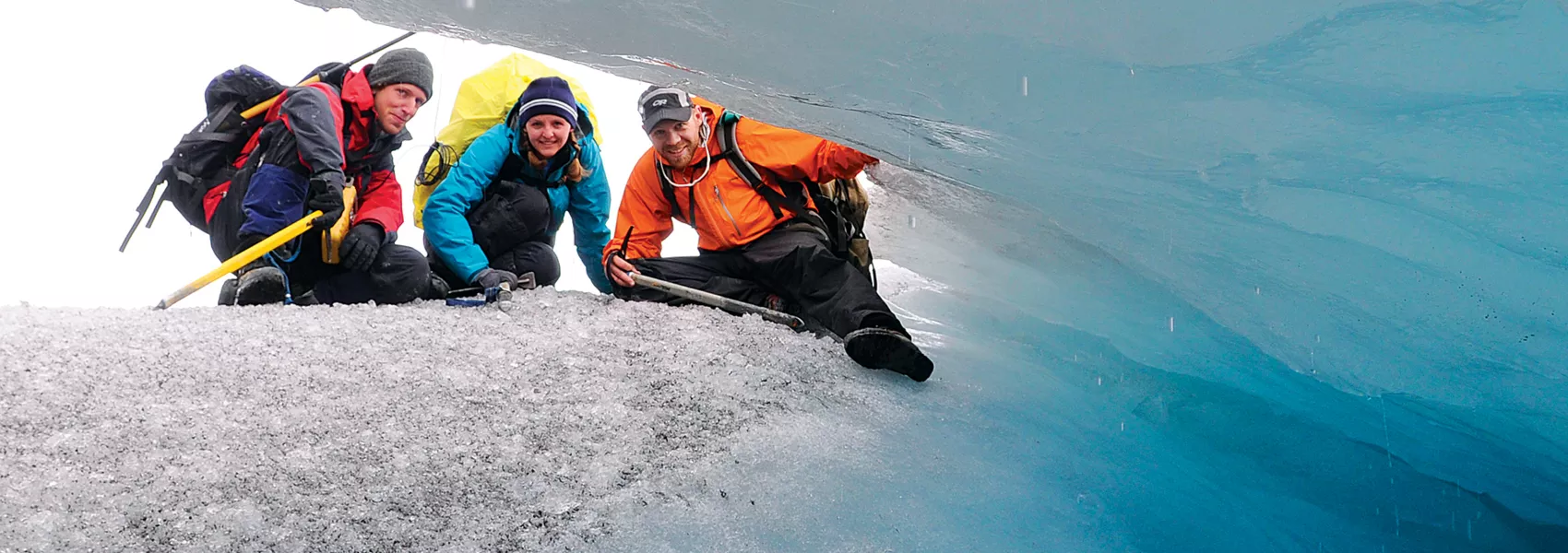 Three students looking at a cave of ice