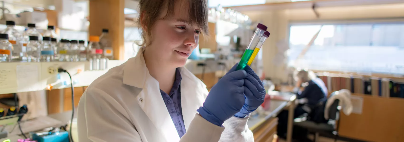 Student in lab coat examining lab equipment