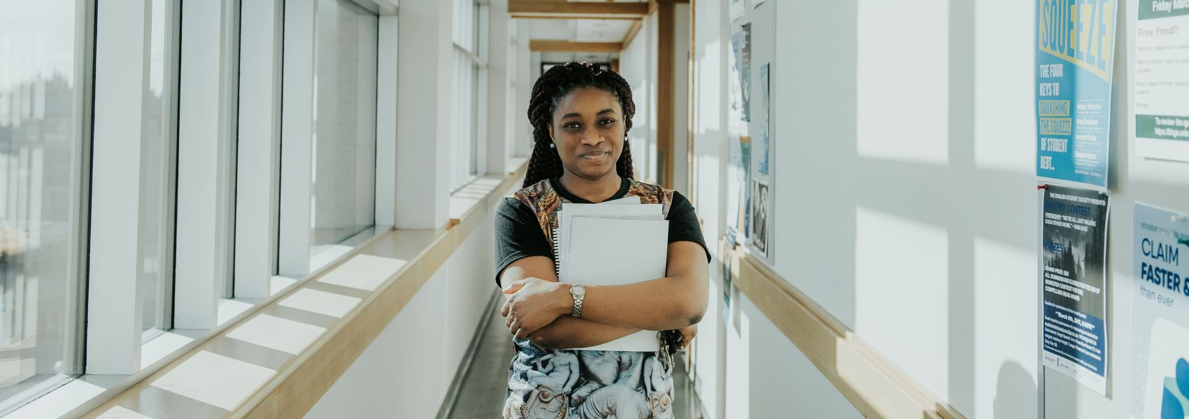 a young woman standing in the hallway of UNBC lab building