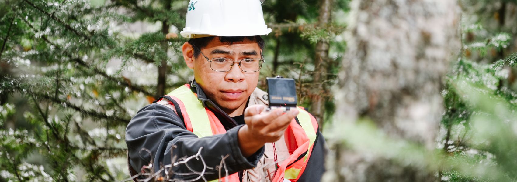 UNBC student in the forest looking at a compass 